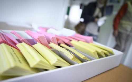 Närbild på en låda med färgsorterade röstsedlar.
