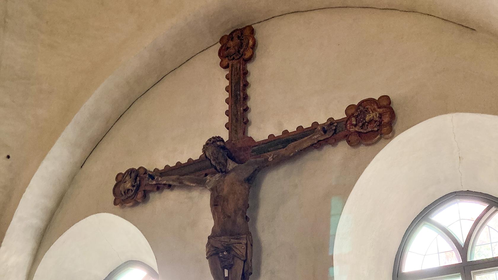 Ett stort krucifix hänger på väggen i en kyrka.