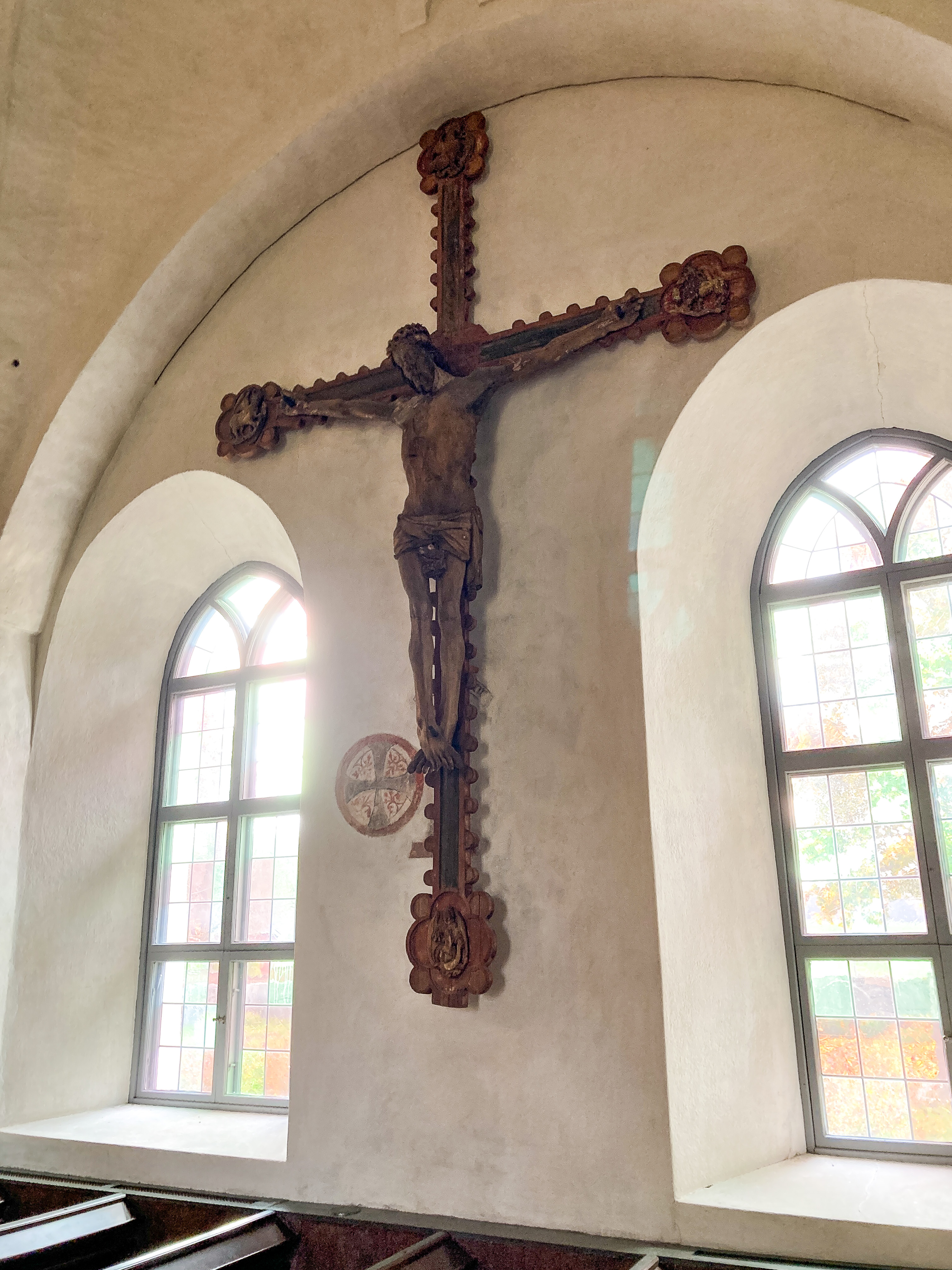 Ett stort krucifix hänger på väggen i en kyrka.