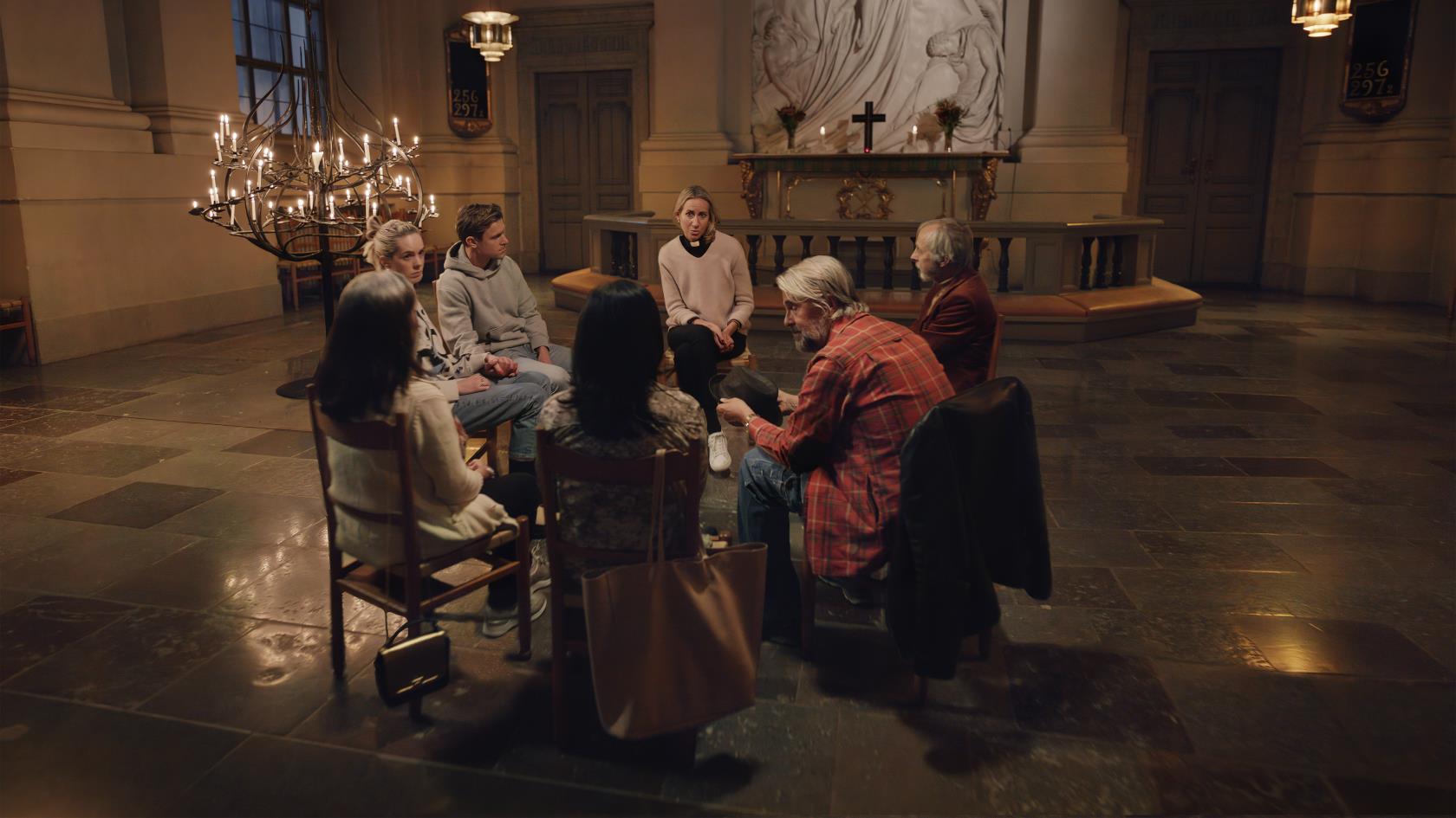 En grupp människor sitter i en ring i kyrkan och samtalar.