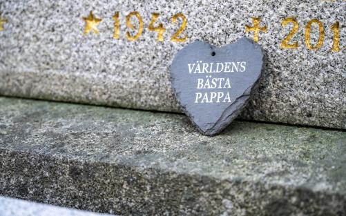 Ett stenhjärta med texten Världens bästa pappa lutar mot en gravsten.