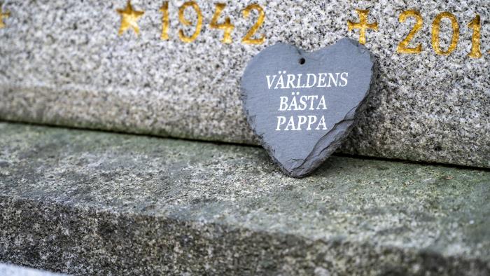 Ett stenhjärta med texten Världens bästa pappa lutar mot en gravsten.