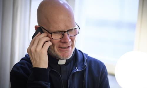 En manlig präst pratar i mobiltelefon.