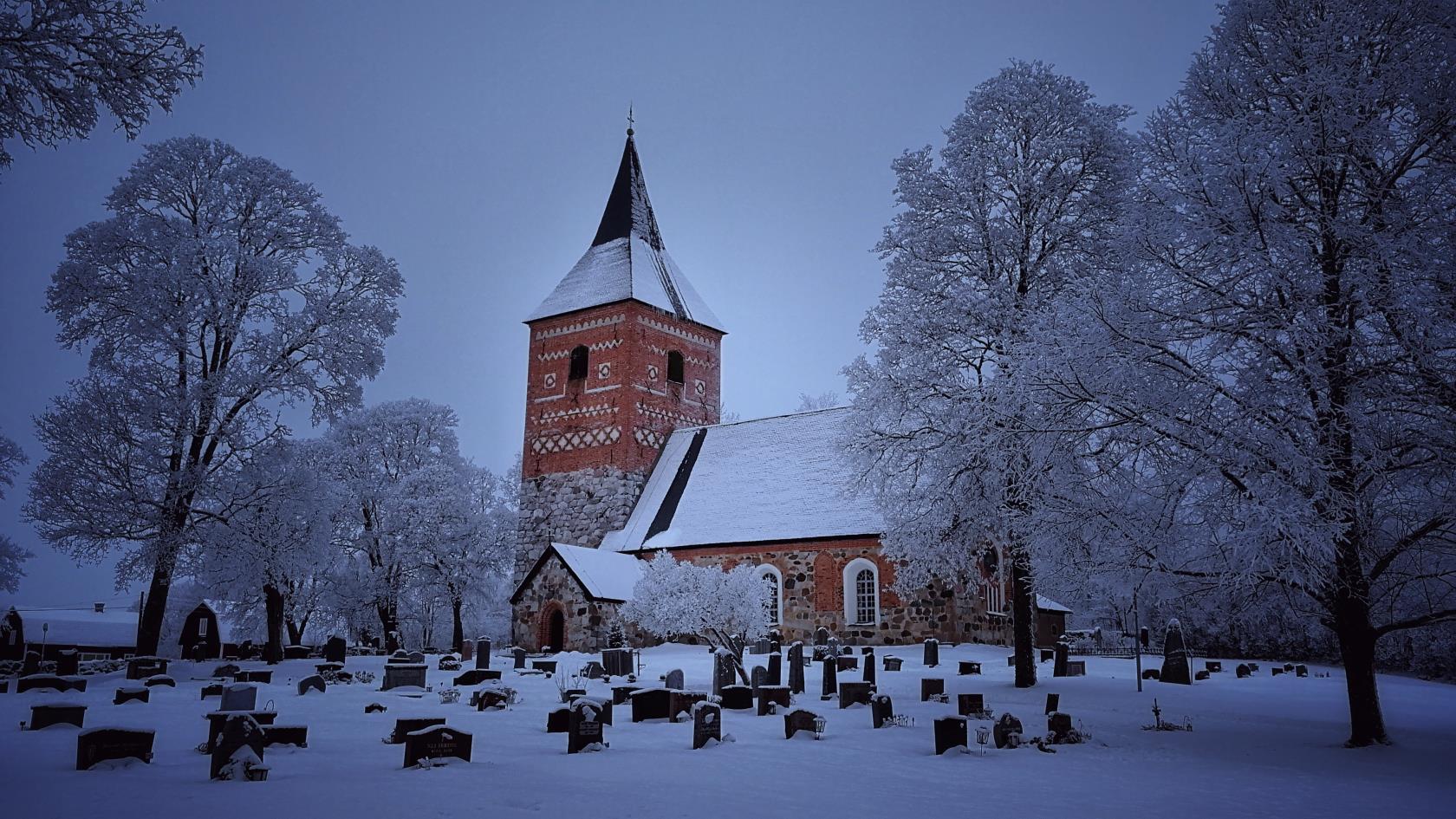 Snötäckt kyrka och kyrkogård