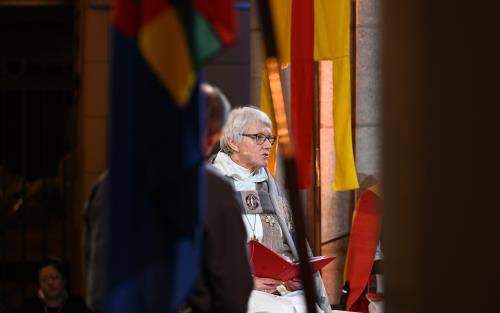 Ärkebiskop Antje Jackelén läser högt i Uppsala domkyrka omgiven av Svenska kyrkans och den samiska flaggan.