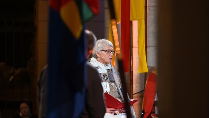 Ärkebiskop Antje Jackelén läser högt i Uppsala domkyrka omgiven av Svenska kyrkans och den samiska flaggan.