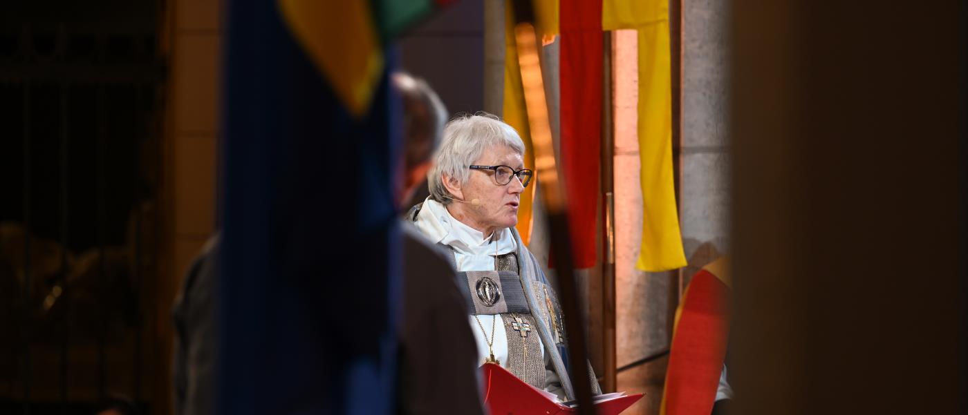 Ärkebiskop Antje Jackelén läser högt i Uppsala domkyrka omgiven av Svenska kyrkans och den samiska flaggan.