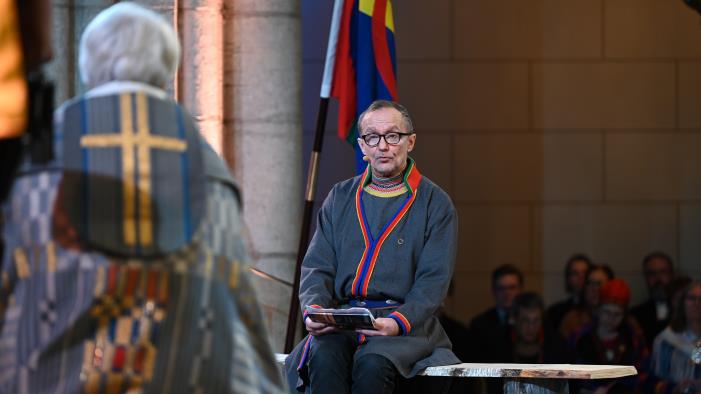 En man i samedräkt sitter mittemot ärkebiskop Antje Jackelén i Uppsala domkyrka.