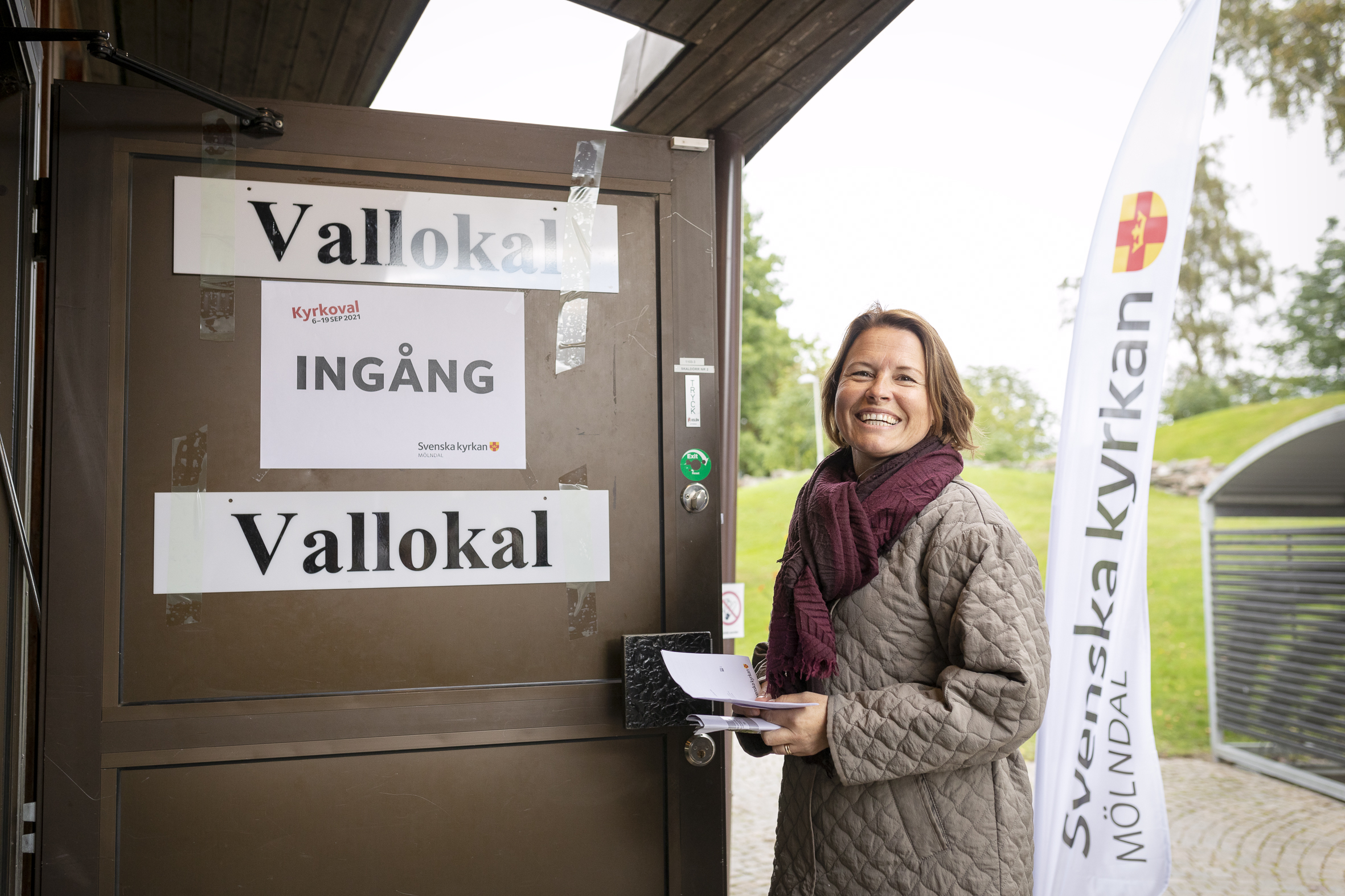 En kvinna står utanför ingången till en vallokal för Kyrkovalet.