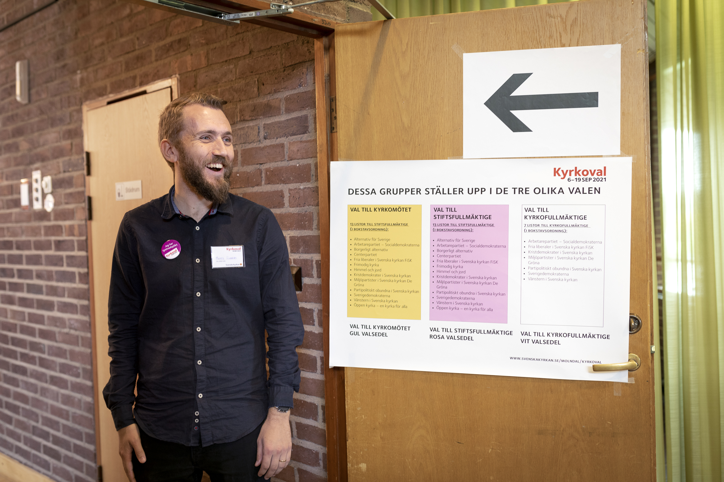 En valarbetare står vid ingången till en vallokal för Kyrkovalet.