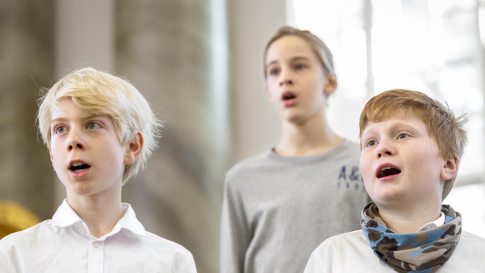 Närbild på medlemmar i en barnkör som sjunger i en kyrka.