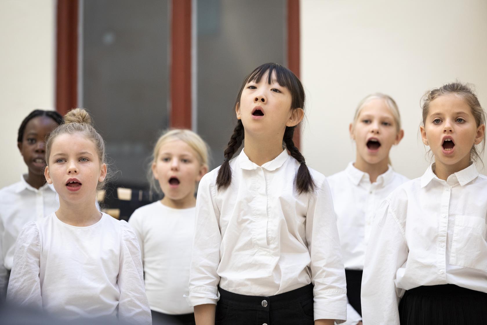 Medlemmar i en barnkör står och sjunger i en kyrka.