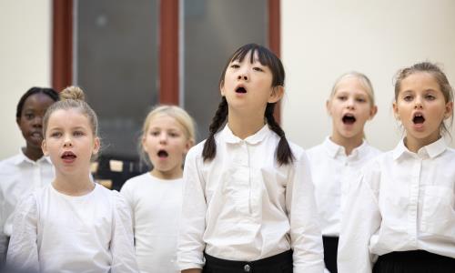 Medlemmar i en barnkör står och sjunger i en kyrka.
