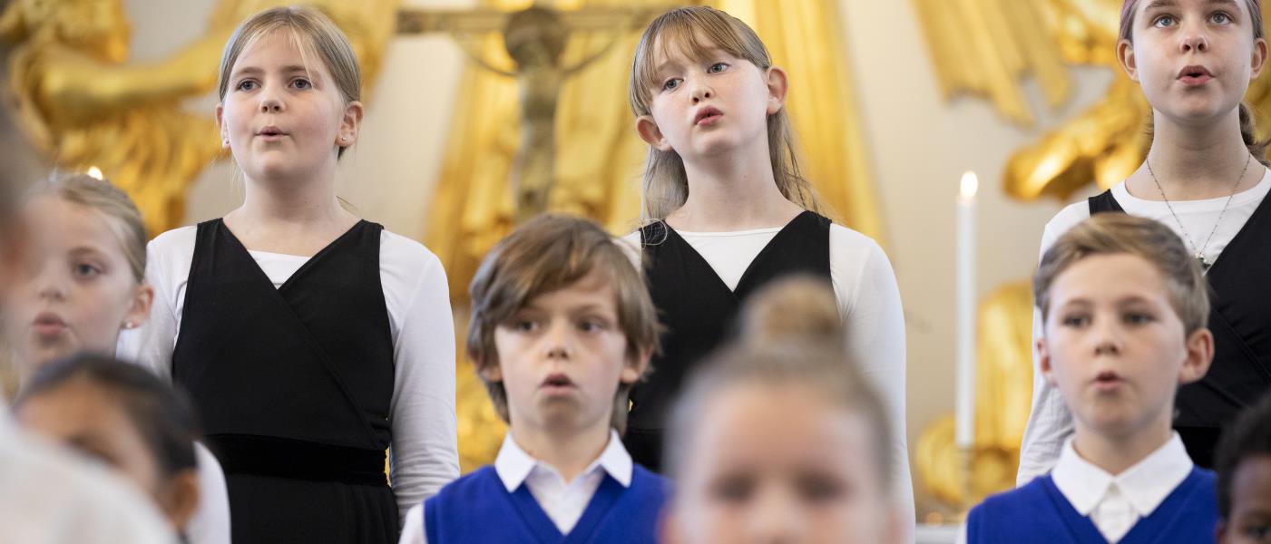 Medlemmar i en barnkör står och sjunger i en kyrka.