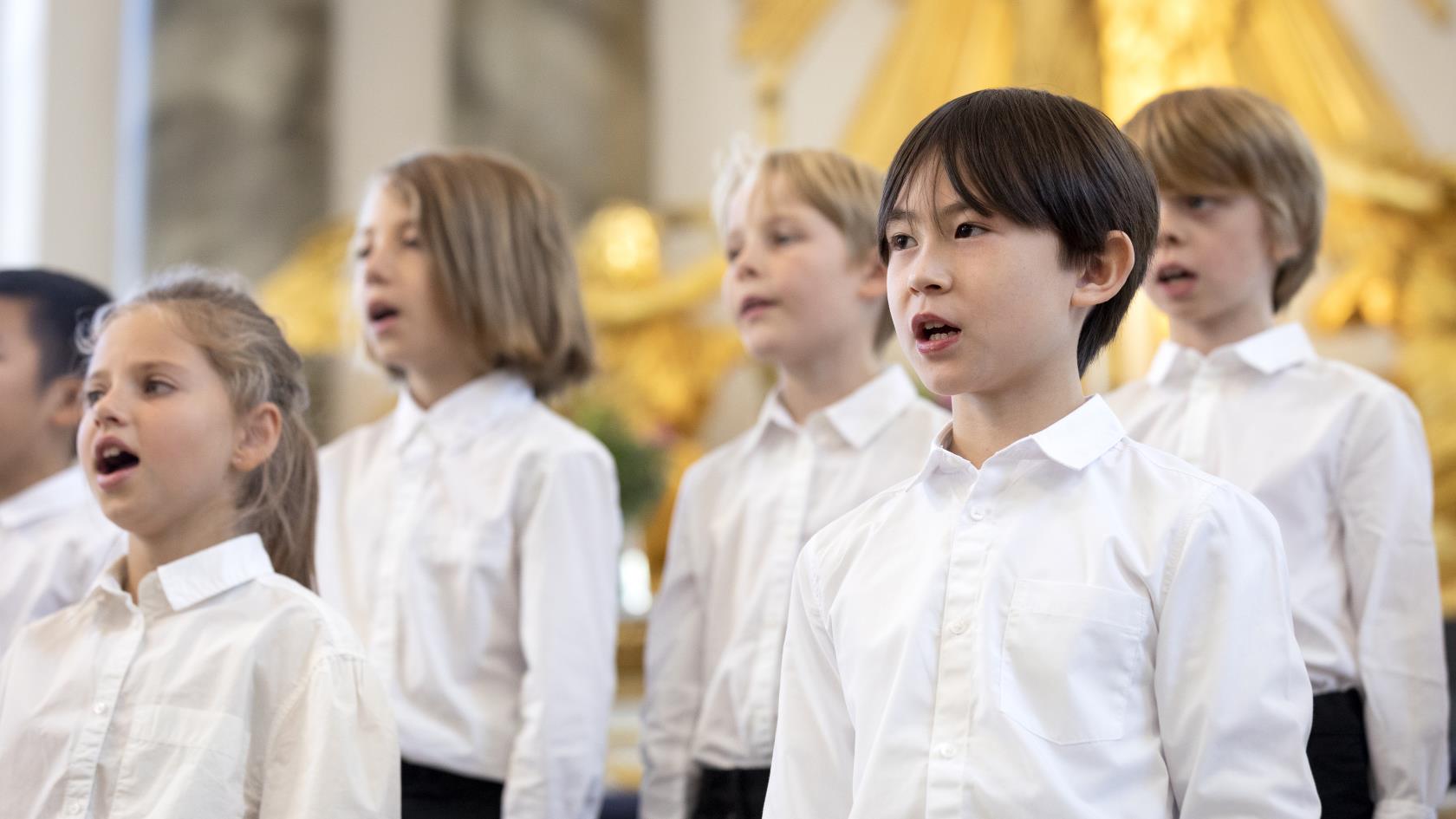 Medlemmar i en barnkör står och sjunger i en kyrka.