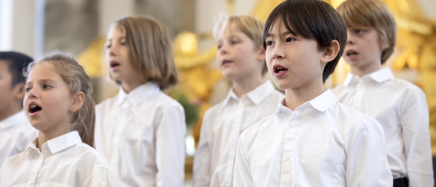 Medlemmar i en barnkör står och sjunger i en kyrka.