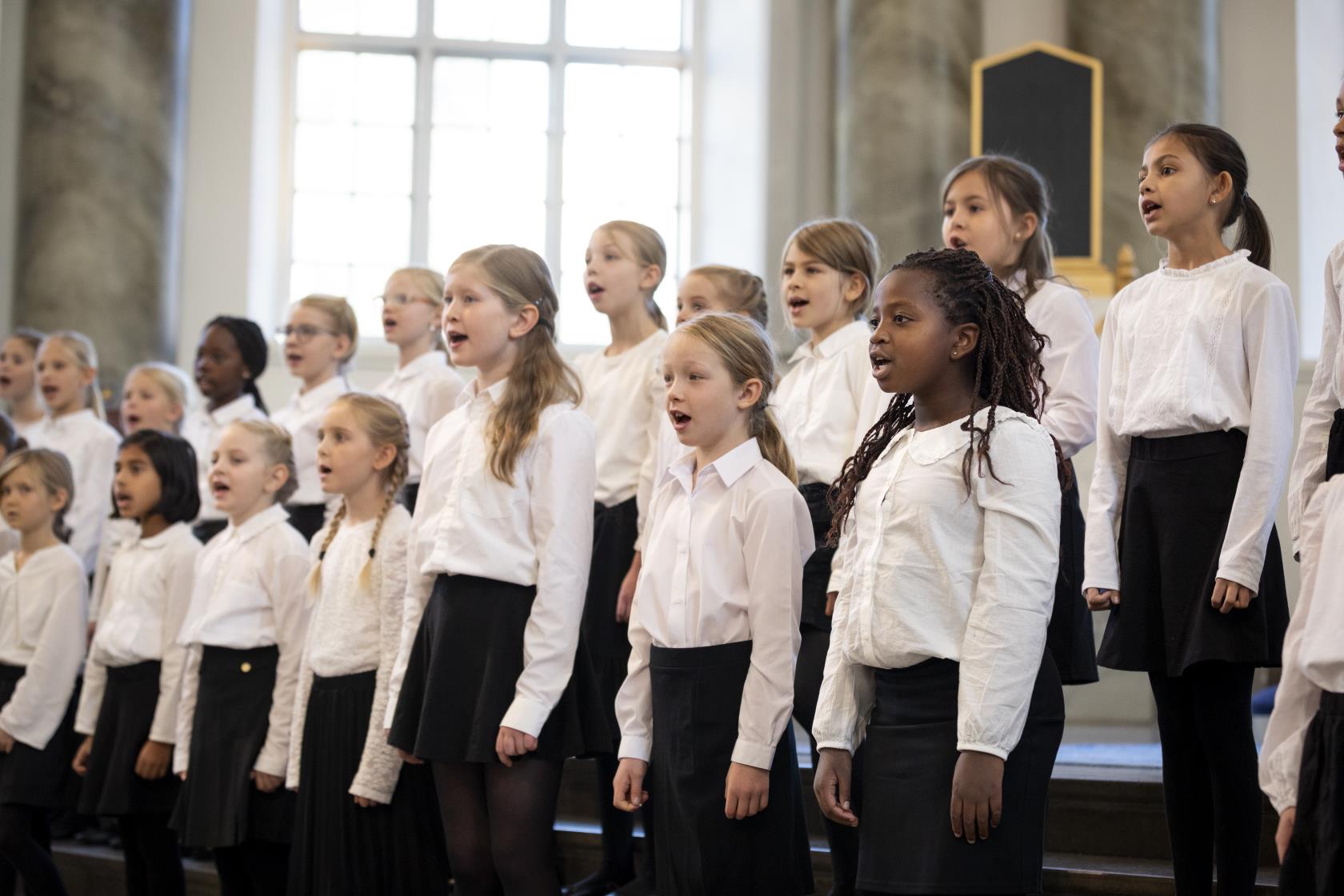 Medlemmar i en barnkör står och sjunger i en kyrka.