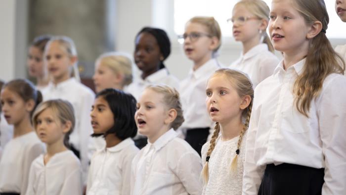 Medlemmar i en barnkör står och sjunger i en kyrka.