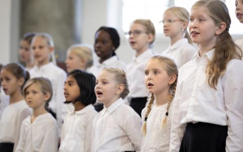 Medlemmar i en barnkör står och sjunger i en kyrka.