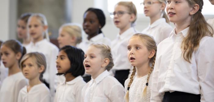 Medlemmar i en barnkör står och sjunger i en kyrka.
