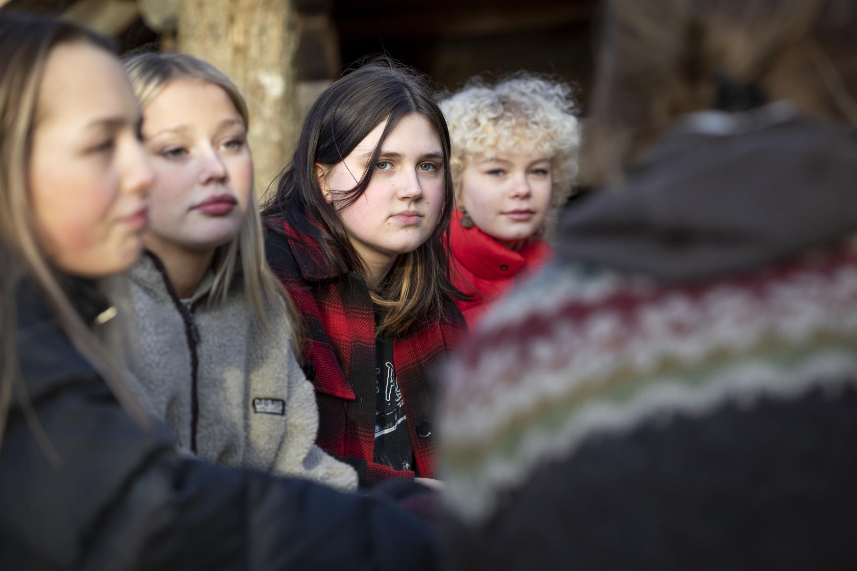 Några tonårstjejer sitter utomhus.