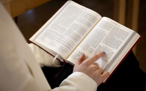 Någon läser ur en bibel och följer texten med fingret.