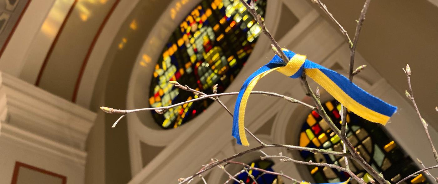 I en kyrka står ett vårris med knutna band i gult och blått.