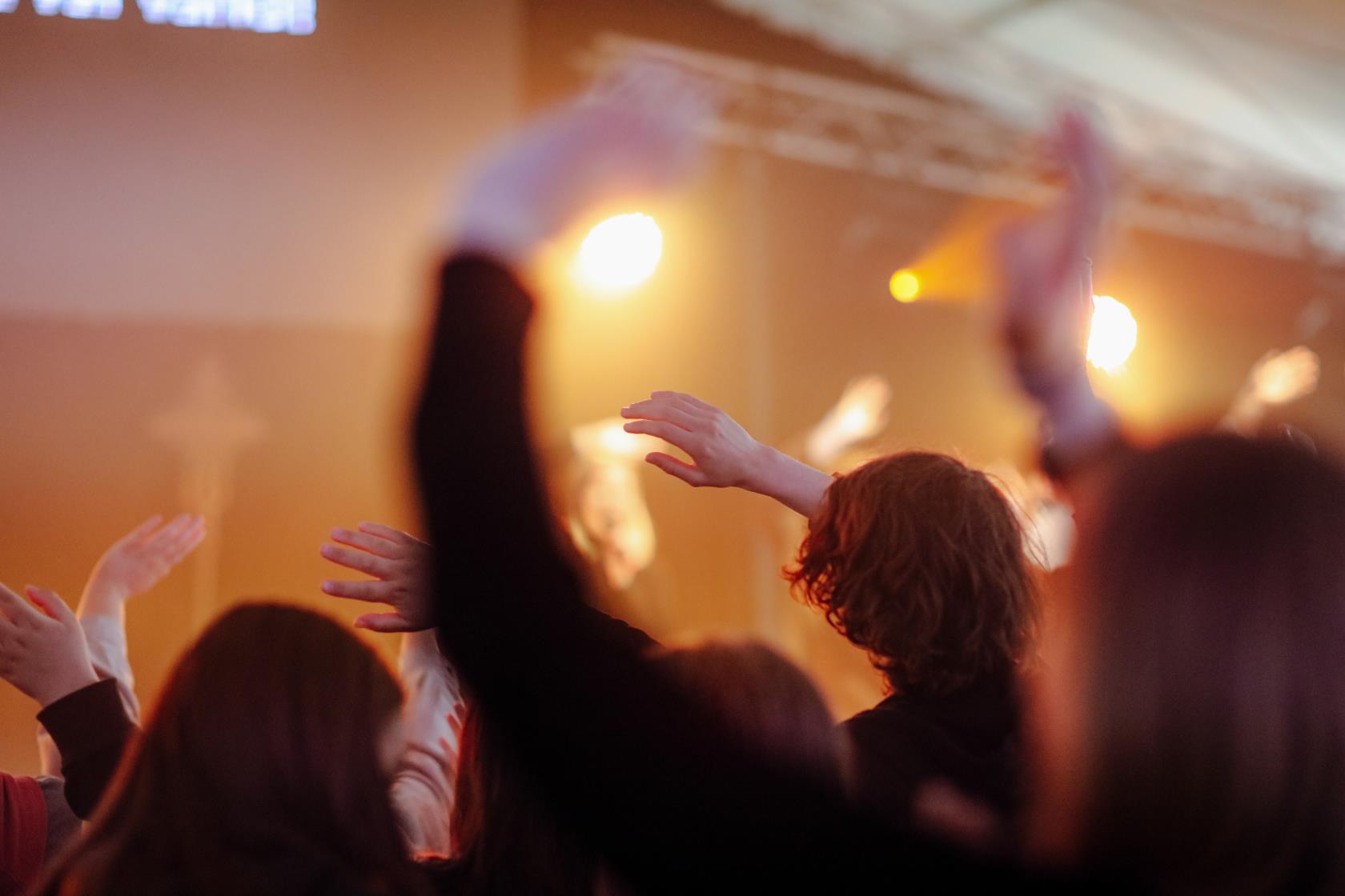 Ungdomar dansar med händerna i luften på ett dansgolv.