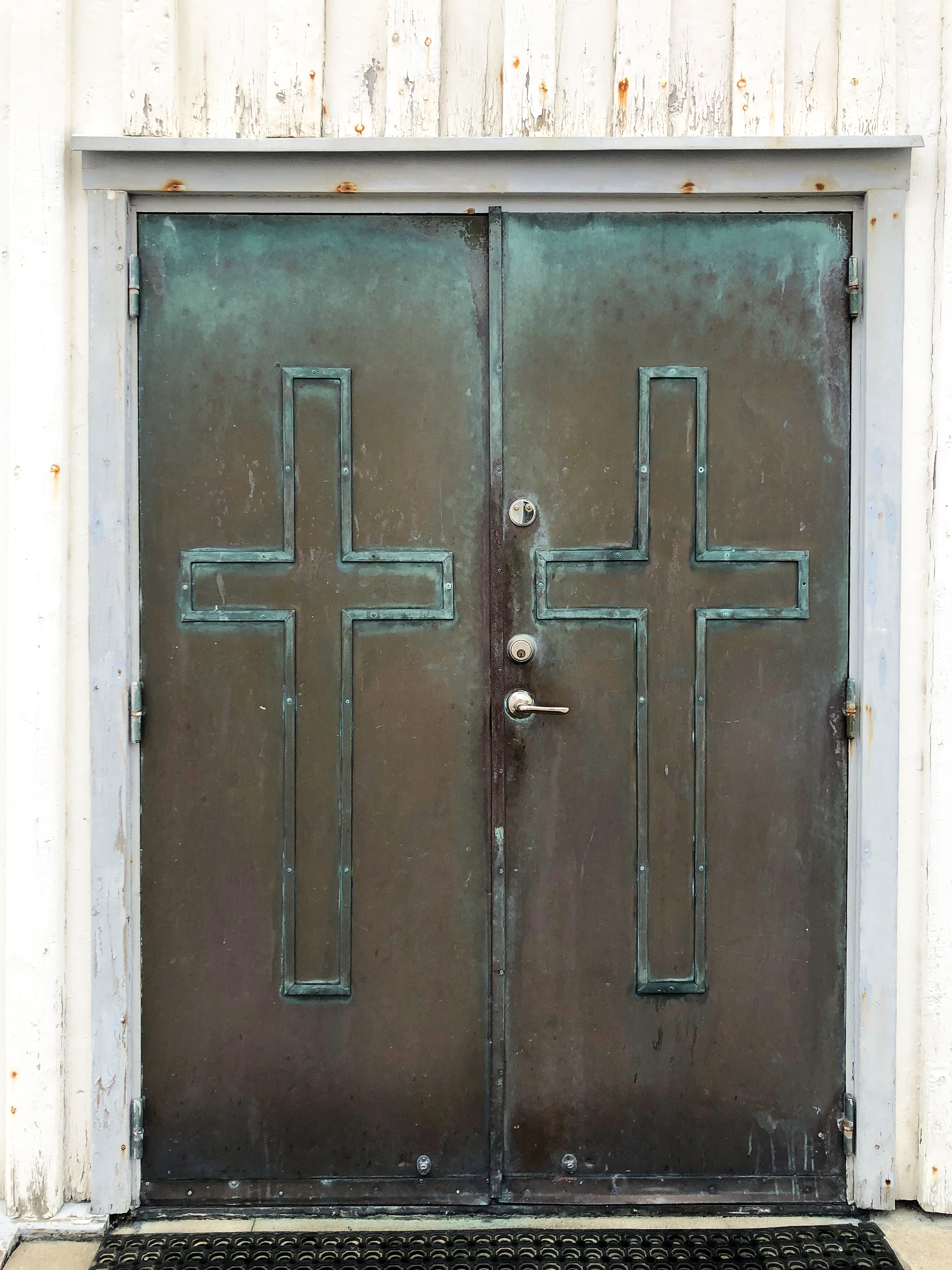Två kors på metalldörrar till en kyrka.