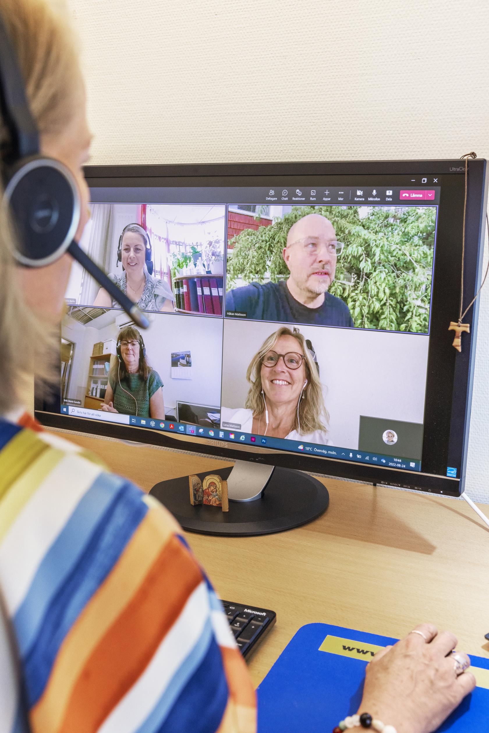 En kvinna med headset har ett videomöte på datorn med fyra andra.