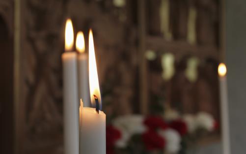 Närbild på brinnande stearinljus i en kyrka.