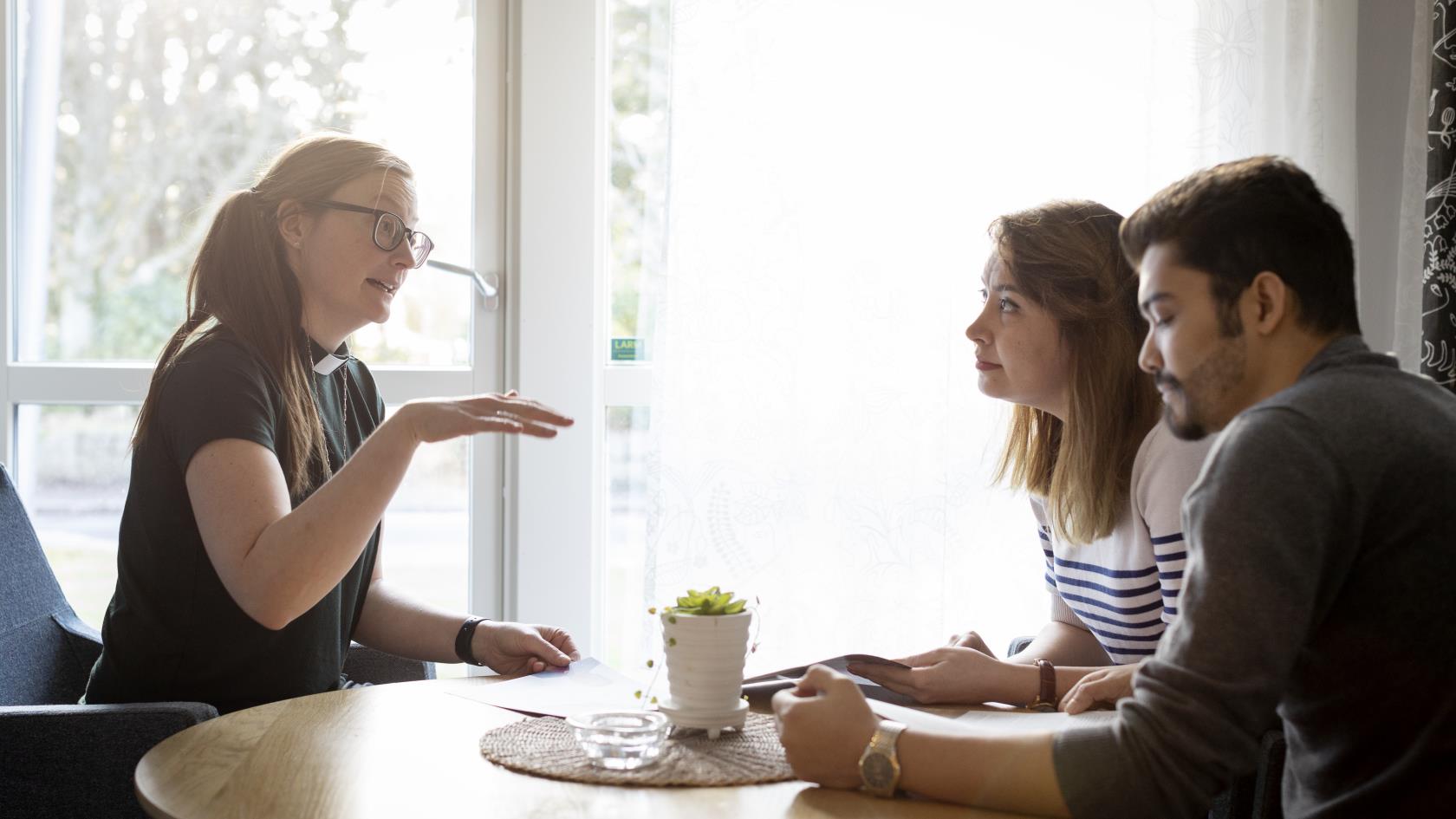 En kvinnlig diakon sitter och samtalar med en man och en kvinna.