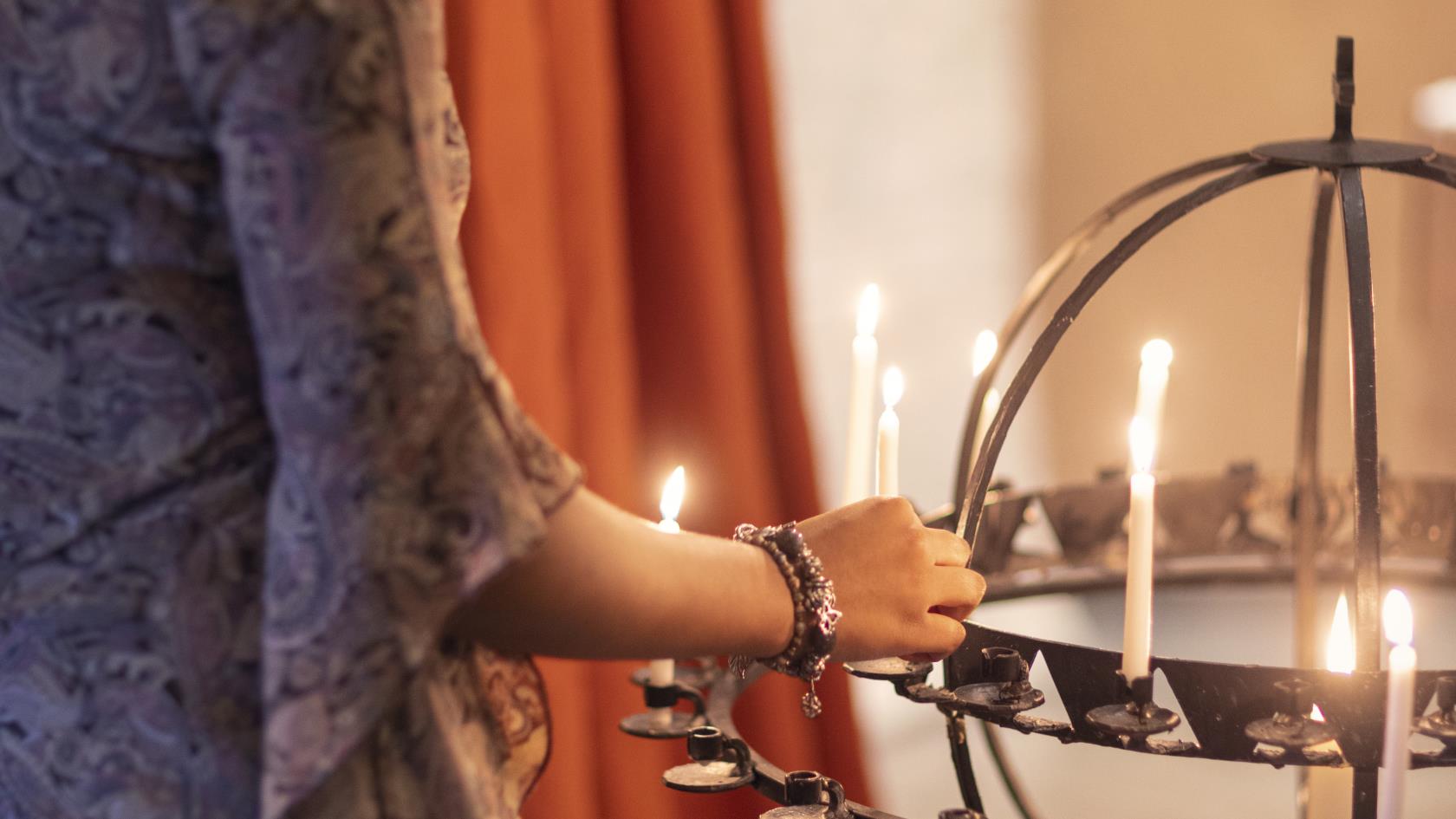 En kvinna sätter ett tänt ljus i en ljusbärare.