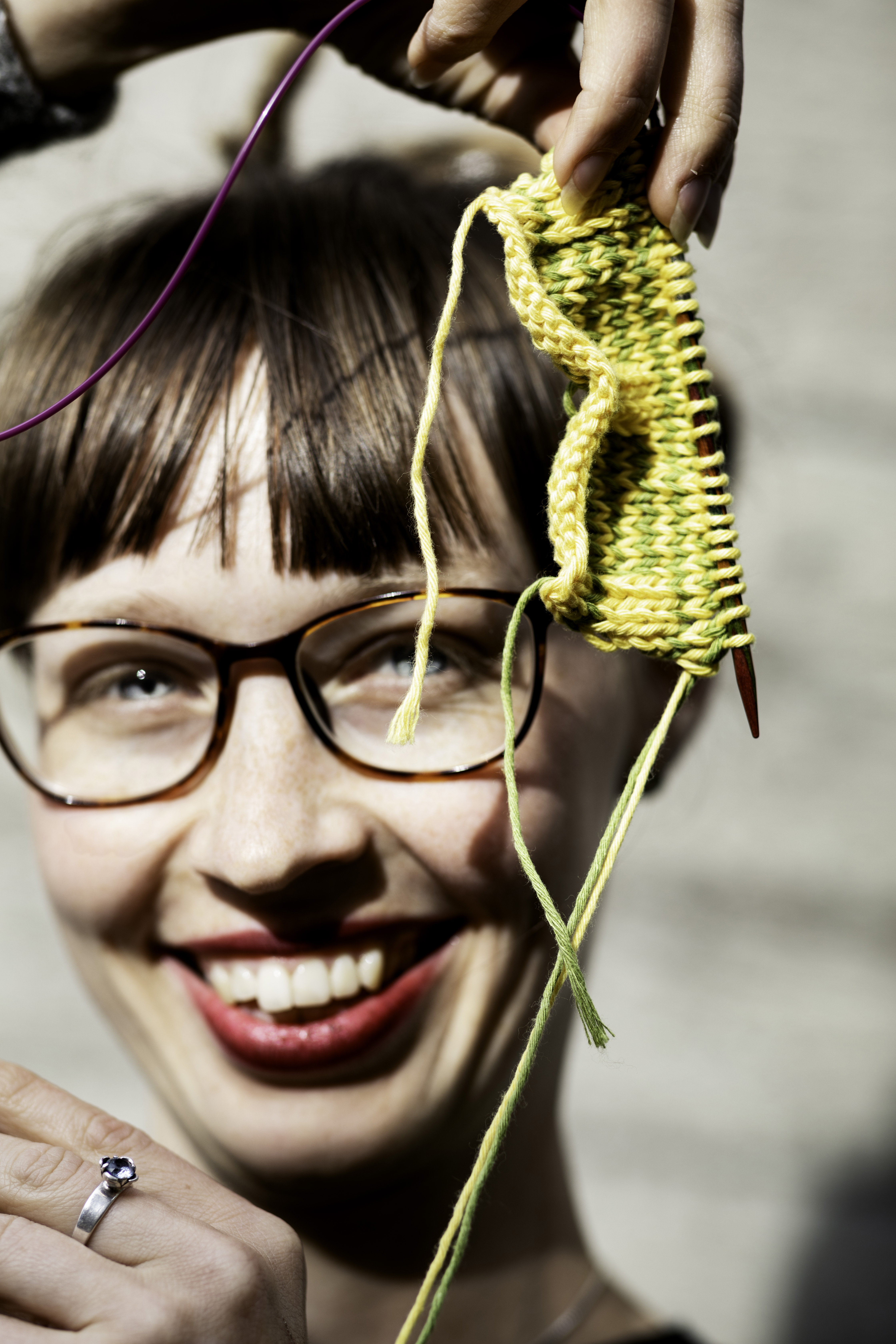 Två glada kvinnor sitter och handarbetar vid ett bord.