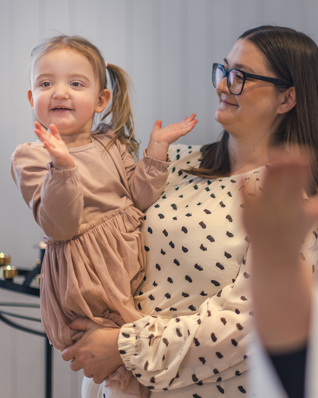 En kvinna bär en liten flicka som klappar händerna. 