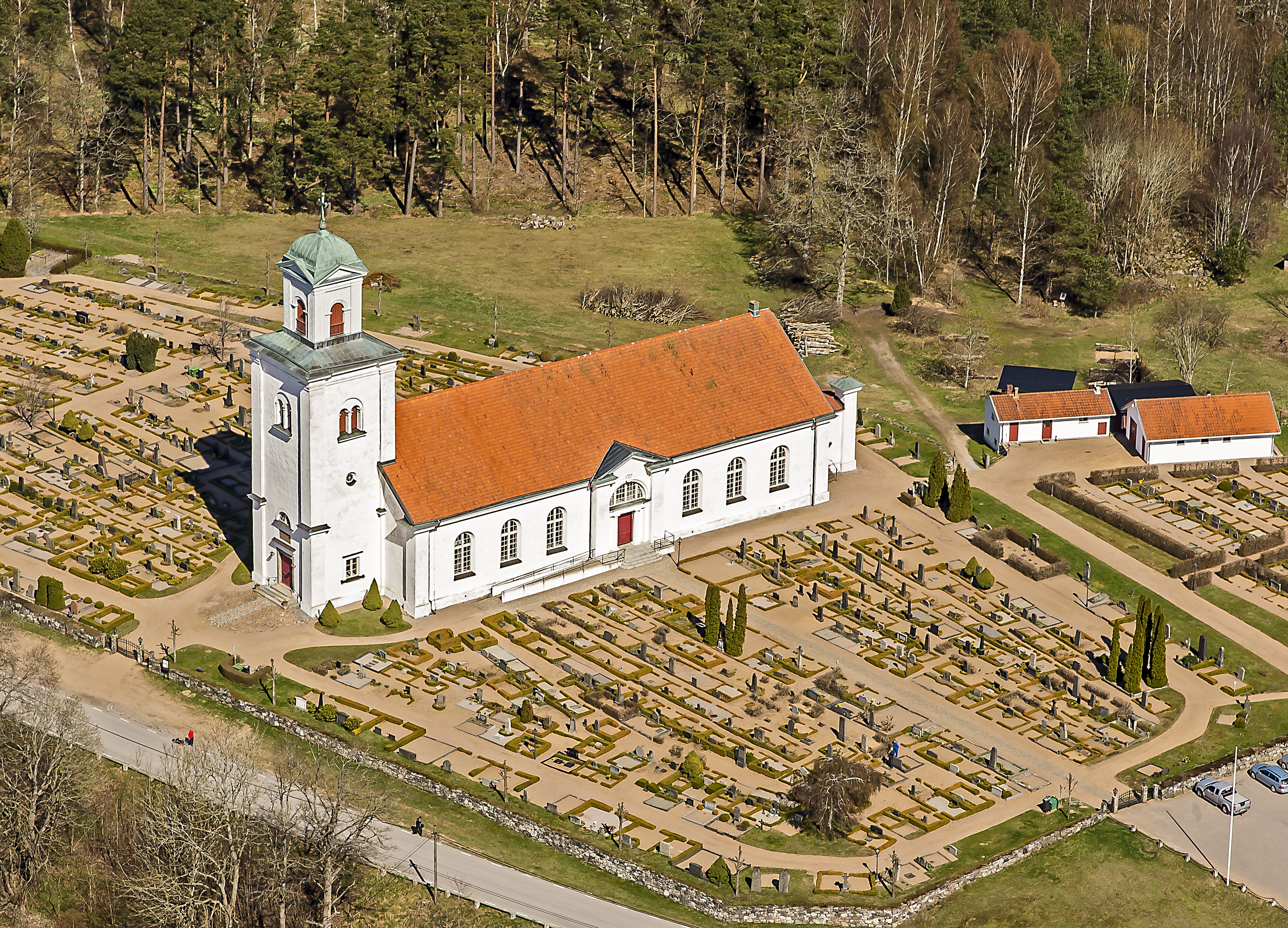 En vitputsad landsbygdskyrka med rött tegeltak och torn.
