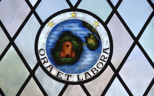 På ett målat fönster står texten Ora et labora (bön och arbete).