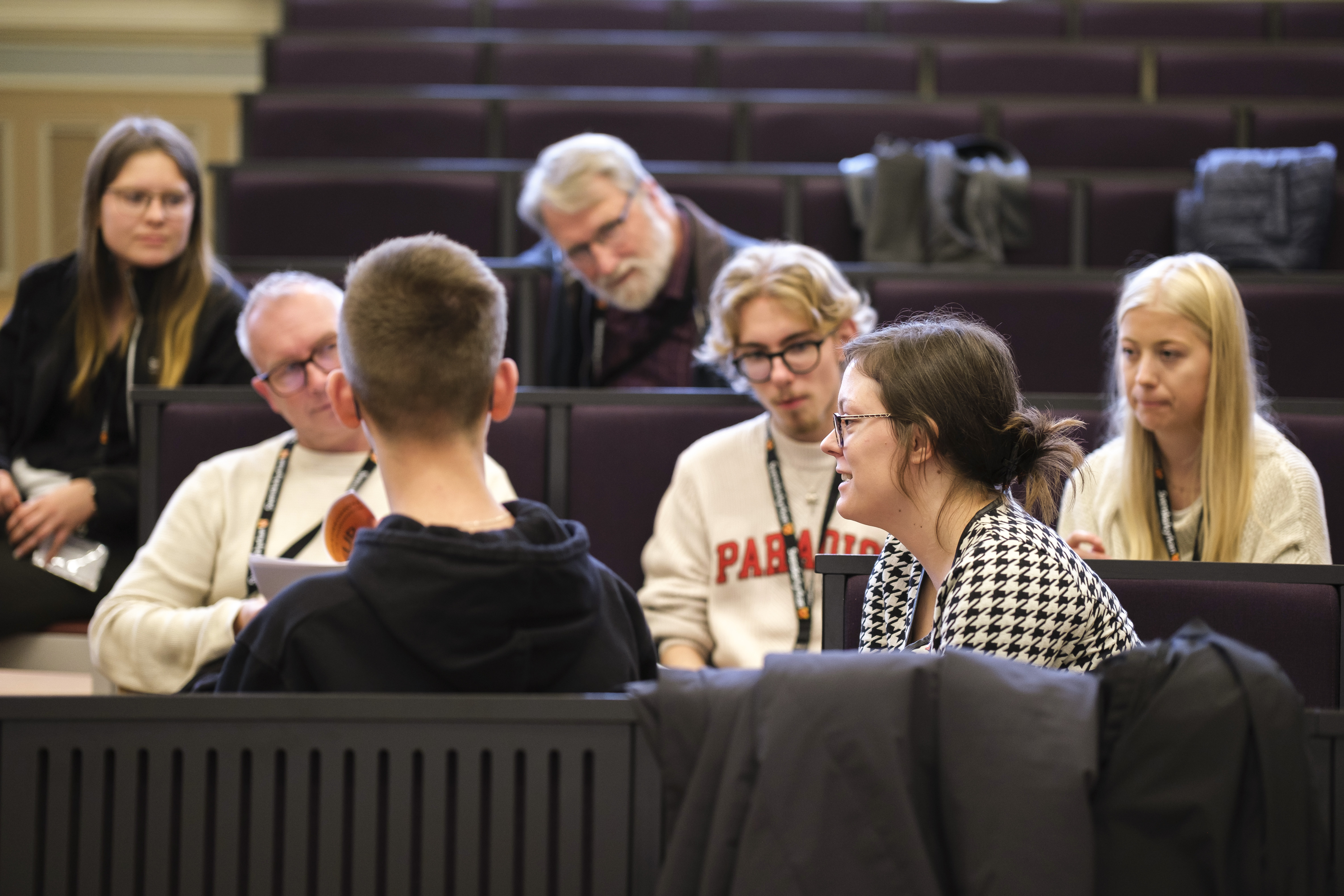 Ett tiotal personer för ett samtal i bänkraderna i en föreläsningssal.