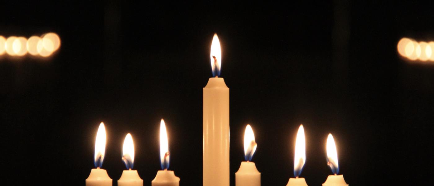 En luciakrona med brinnande ljus i en mörk kyrka.