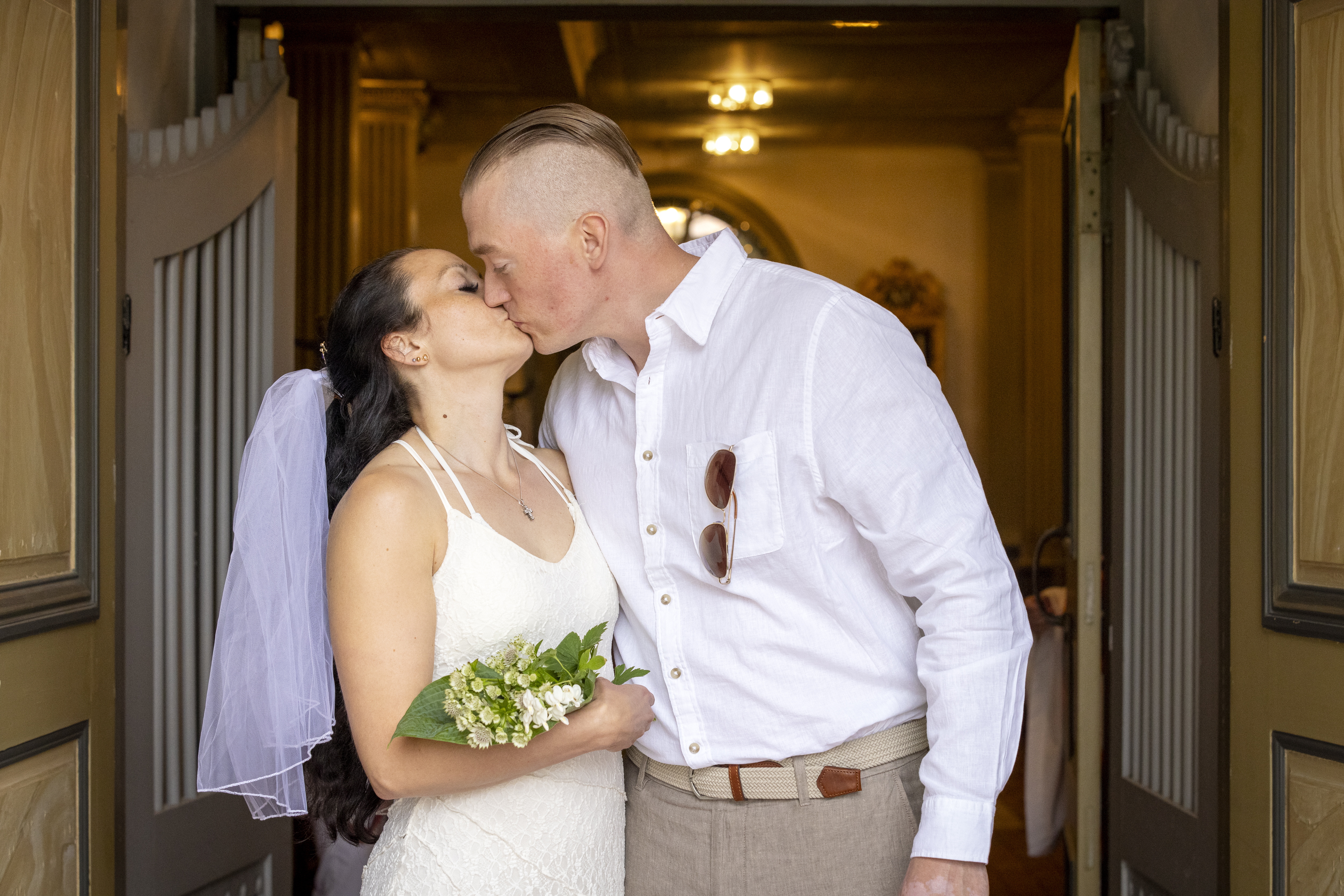 Drop-in vigsel i en kyrka. Ett brudpar står i dörröppningen och kysser varandra.