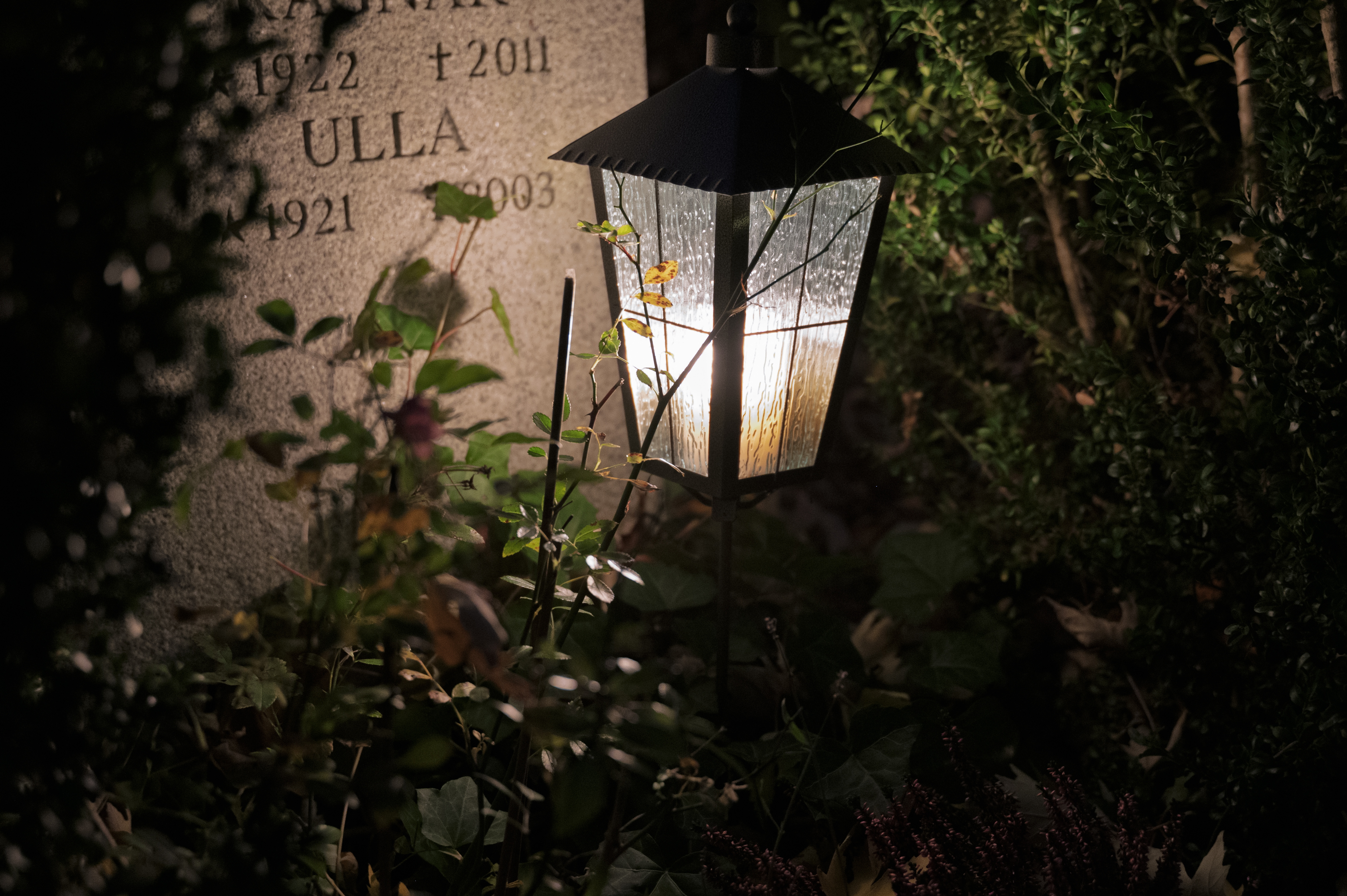 En lykta lyser vid en gravsten.