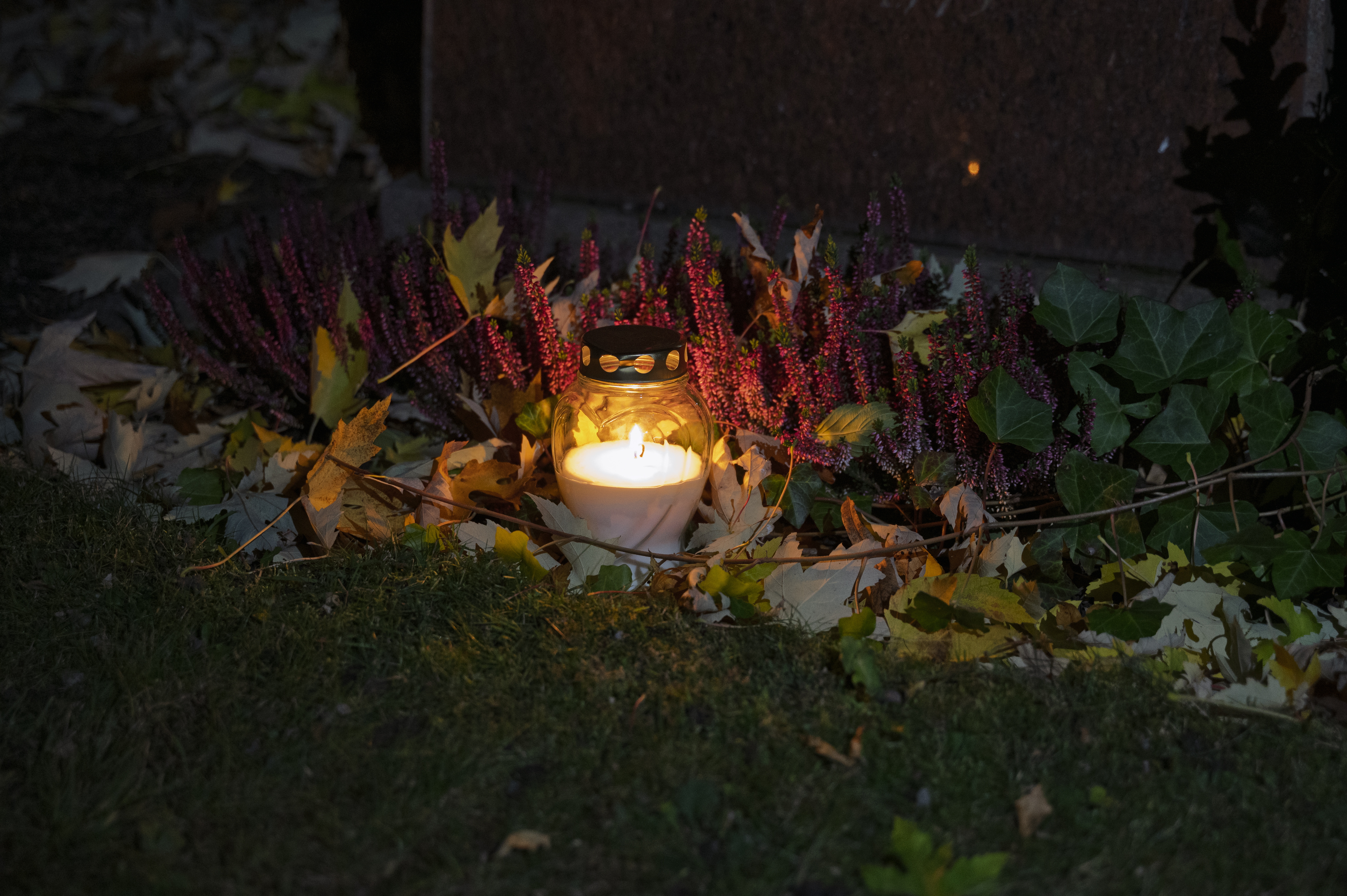 Ett ljus lyser vid en gravsten.