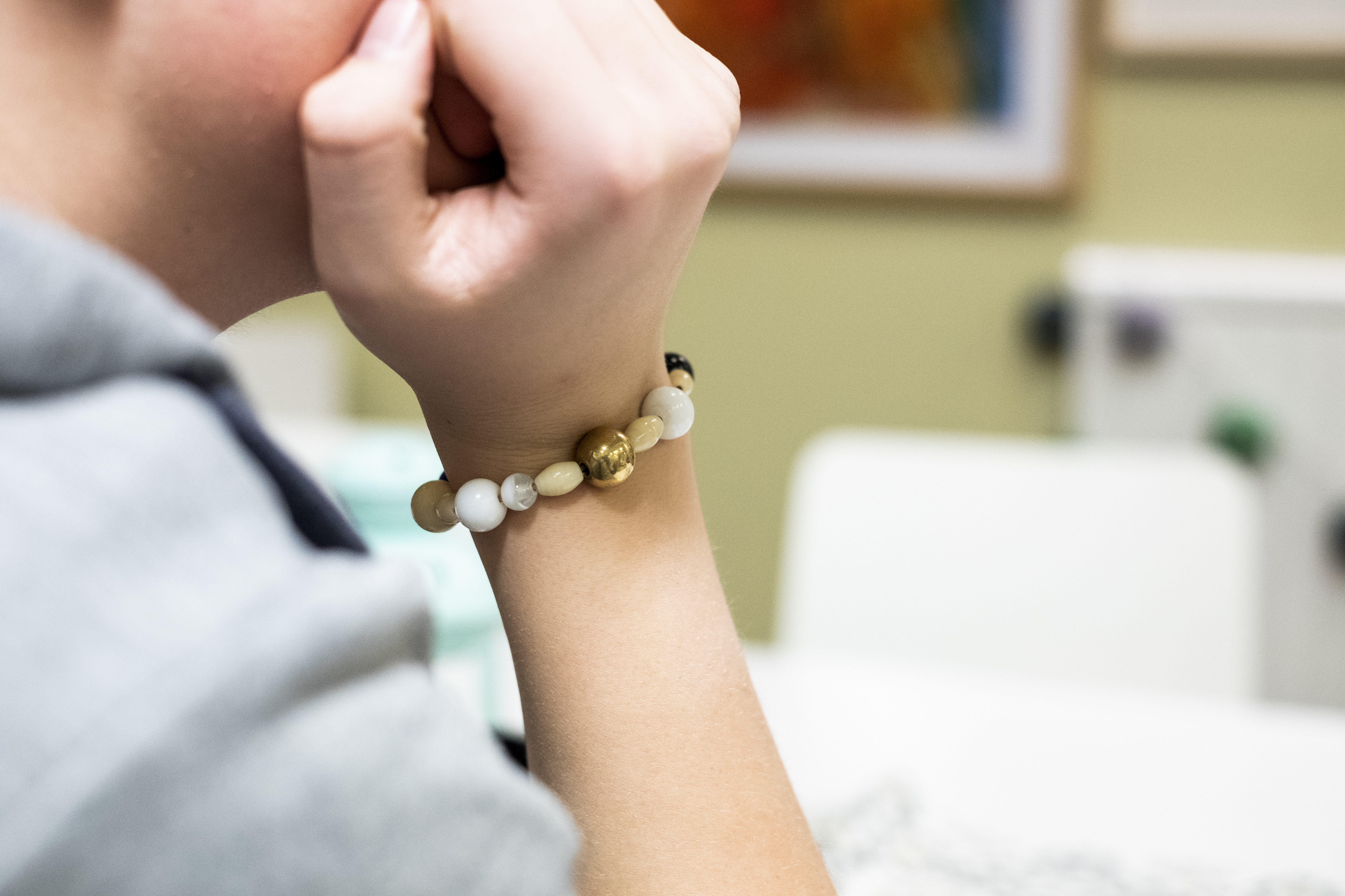 En person lutar handen mot kinden. En frälsarkrans sitter runt handleden.