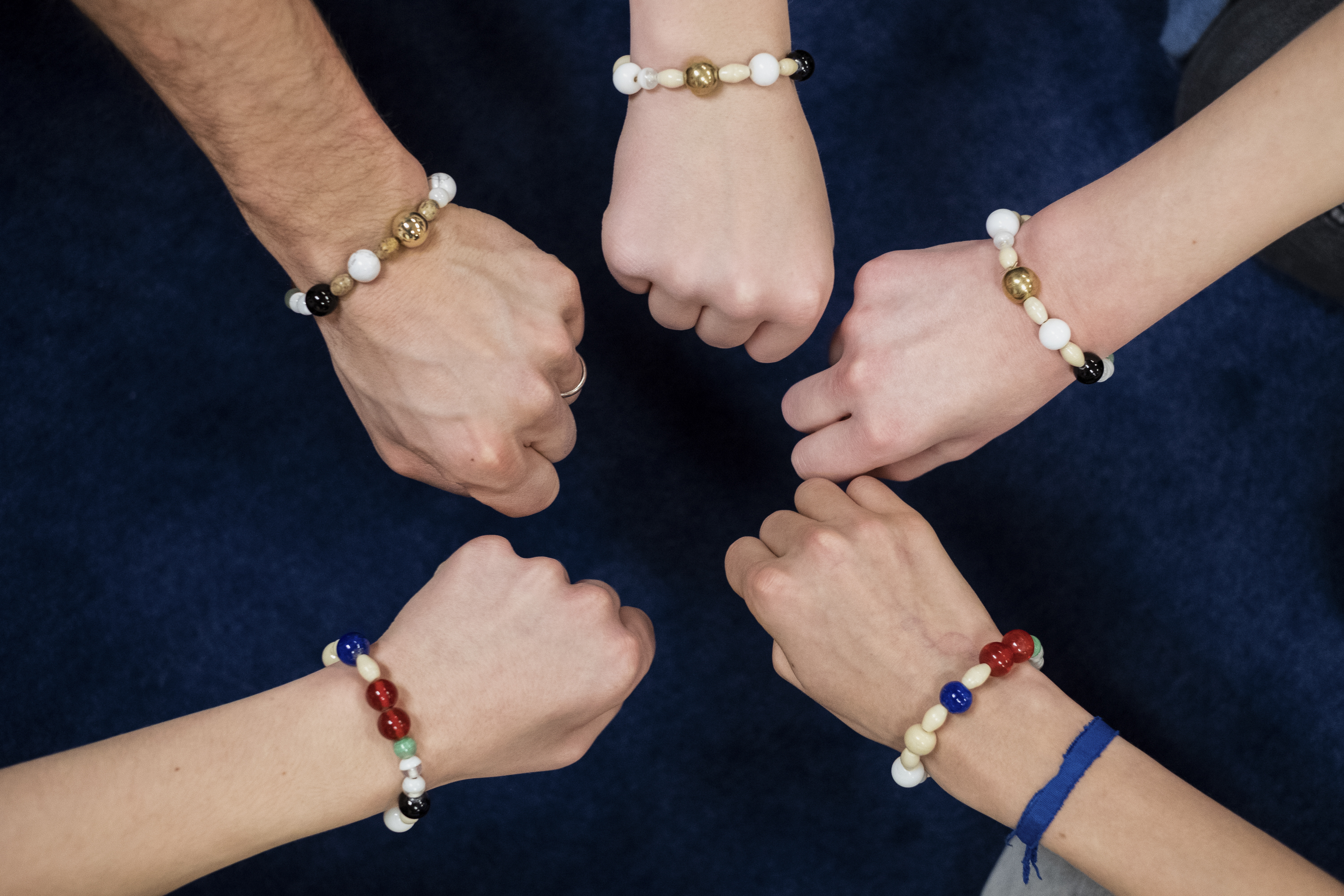 Fem händer som bär frälsarkransen runt handleden knyter nävarna i en ring.