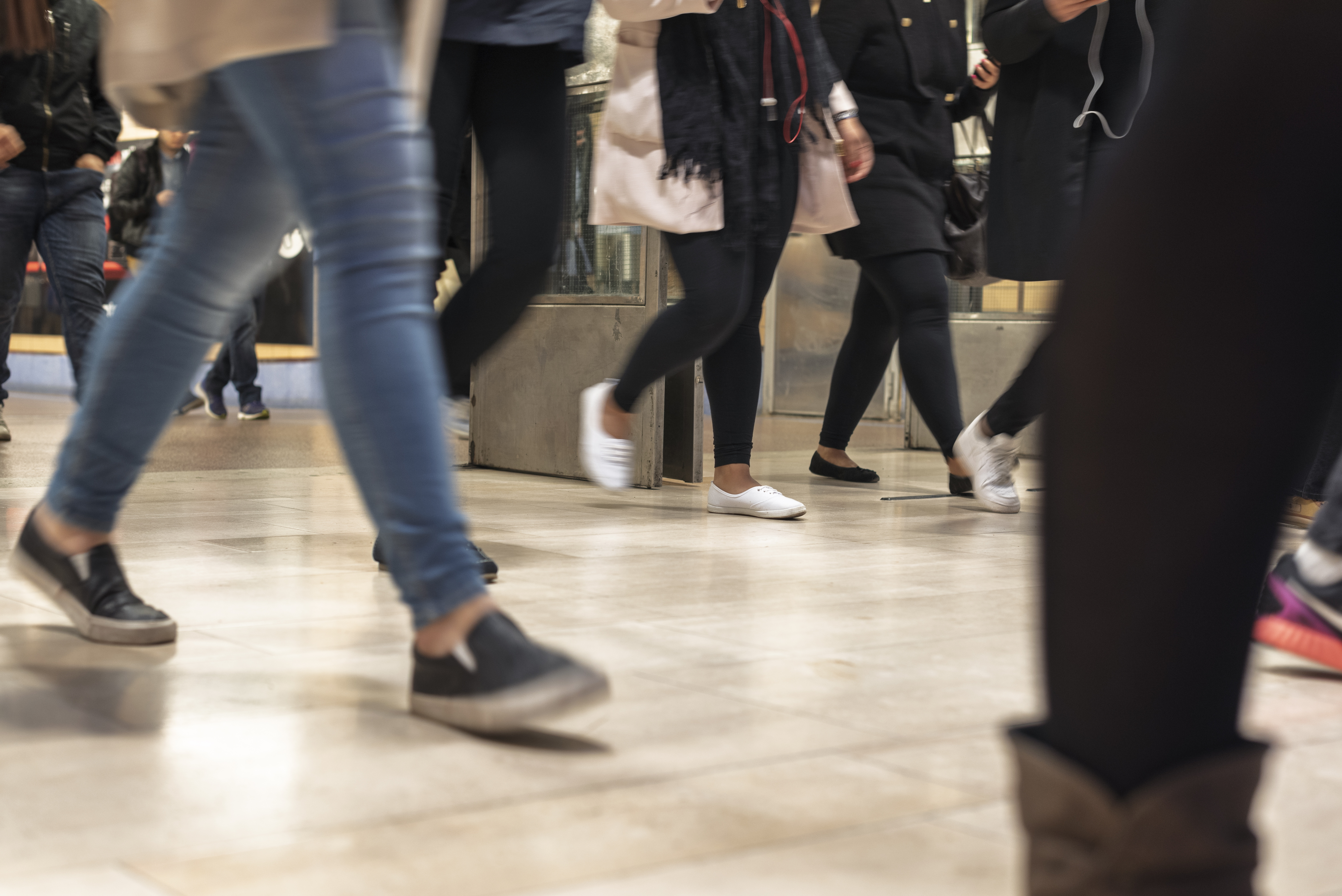 Flera människor rör sig över ett golv. Suddiga ben i förgrunden.