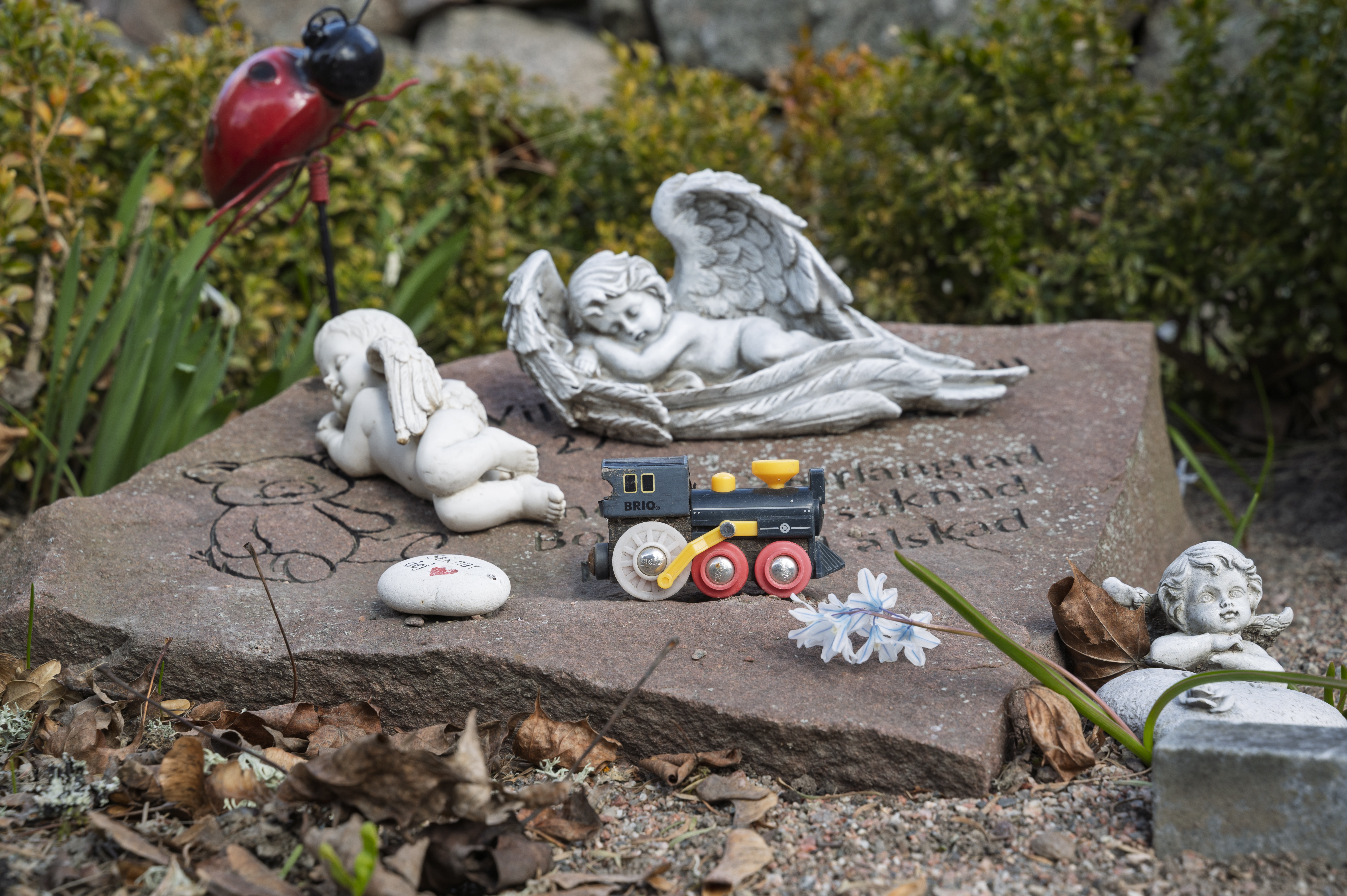 En liggande gravsten med änglar i sten och ett litet lok på.