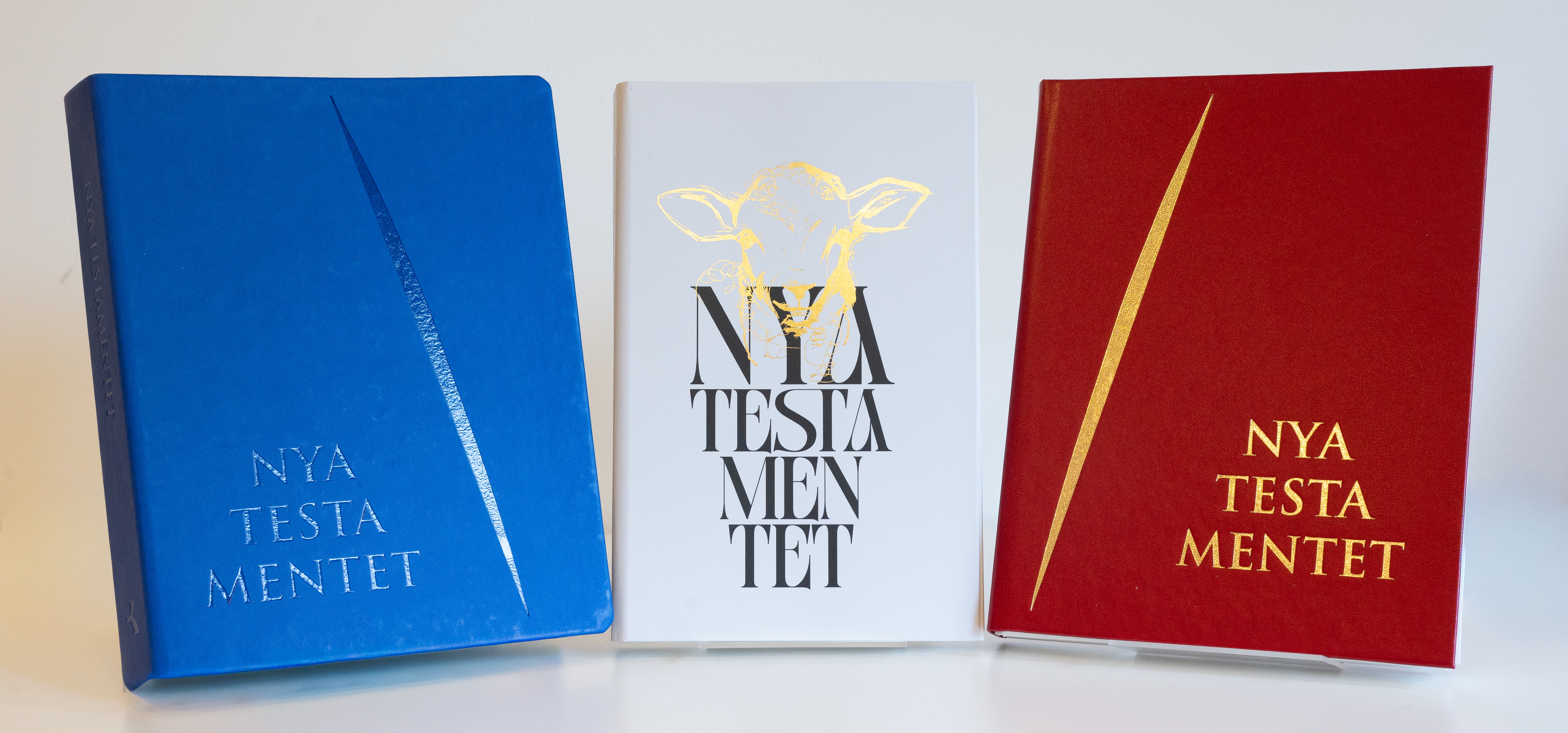 Provtryck av boken NT2026, röd, blå och vit pärm.