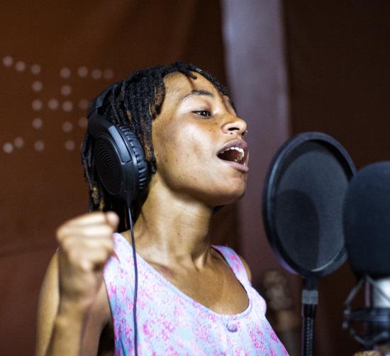 En kvinna sjunger i en musikstudio. 