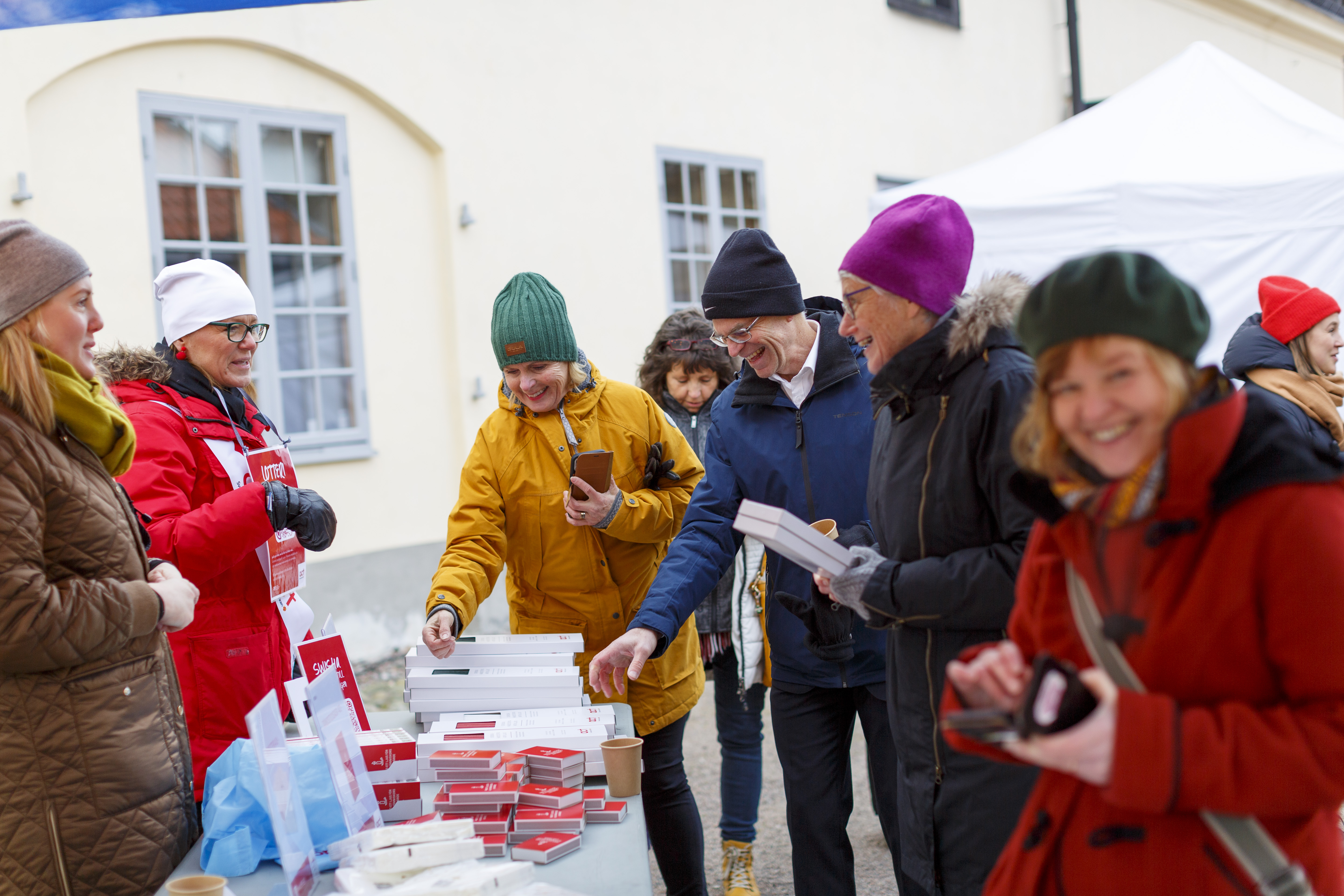 Arbetare från Act Svenska kyrkan står utomhus och säljer ljus och tändstickor.
