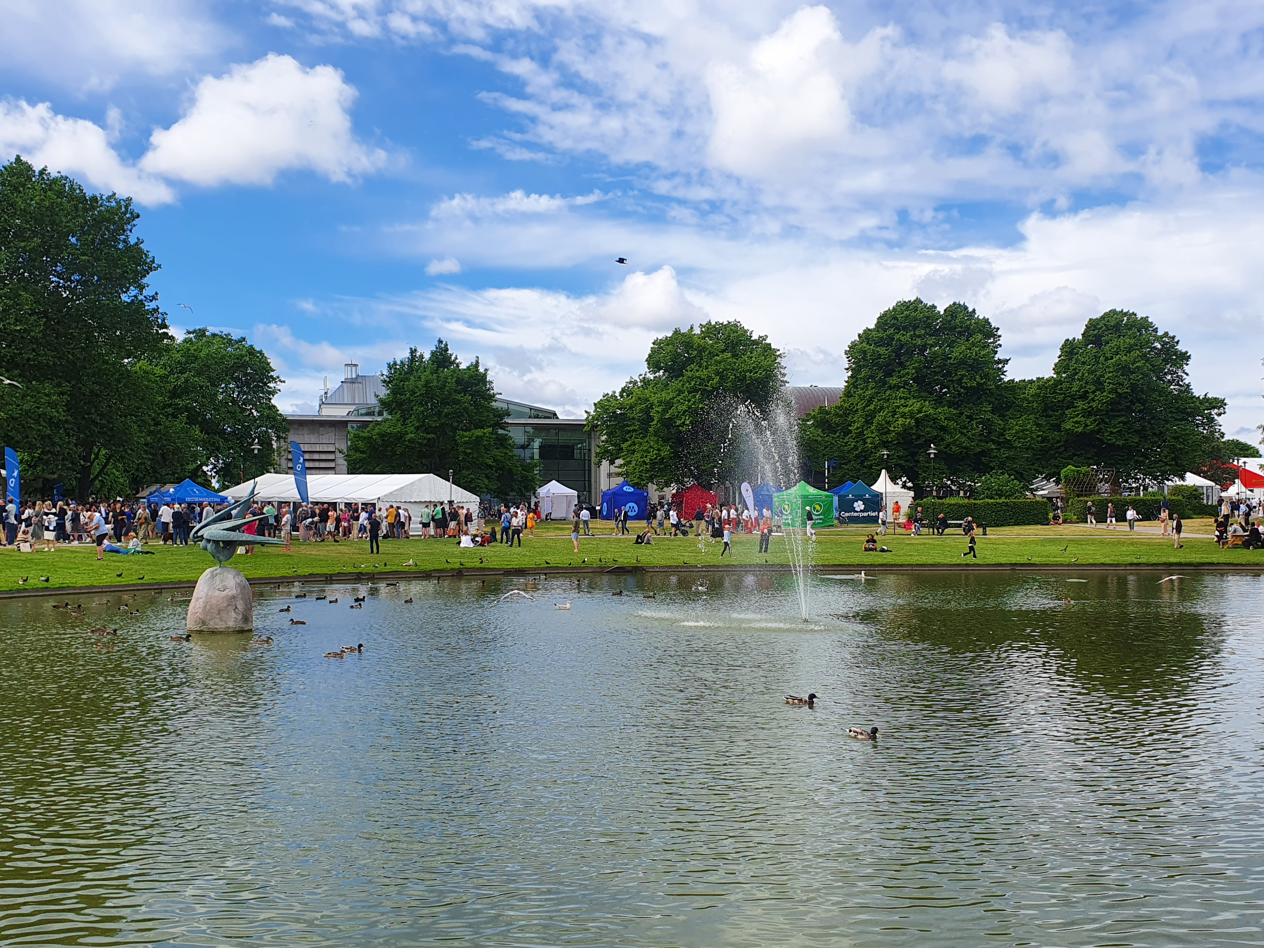Politikertält och människor bortom en damm.